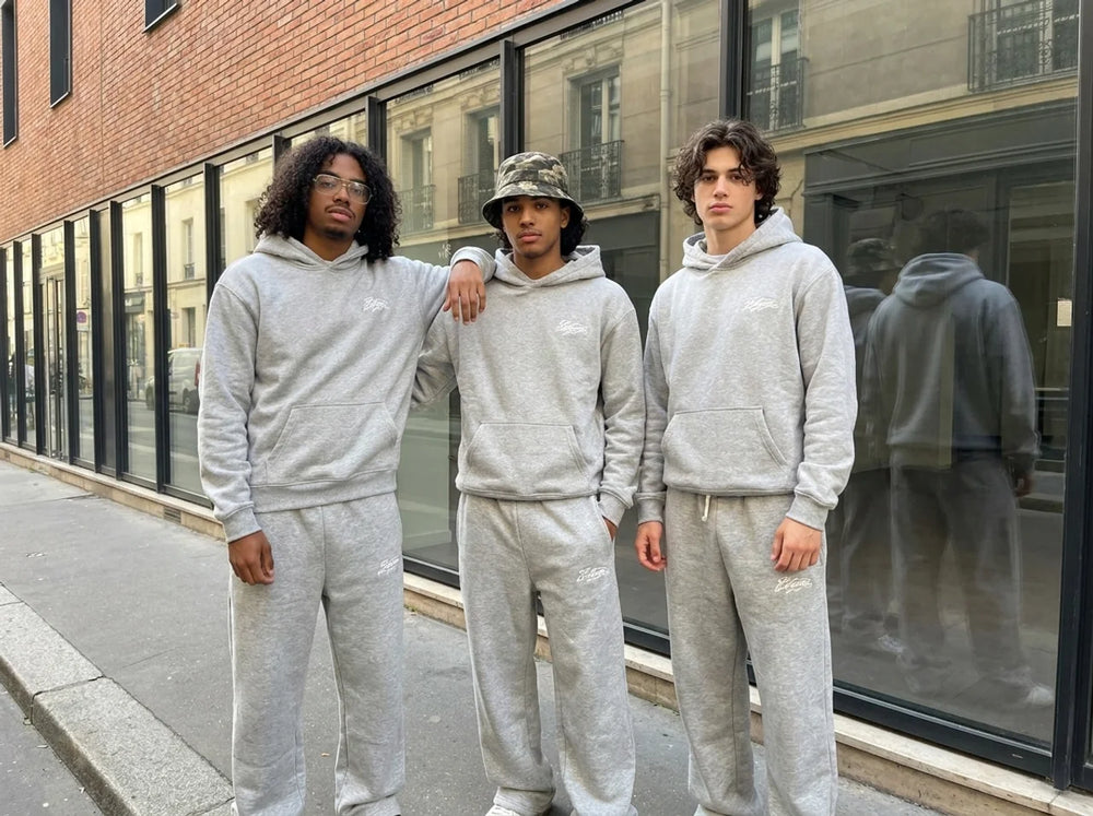 Three people on a city street wearing grey ELEGANT hoodies and sweatpants