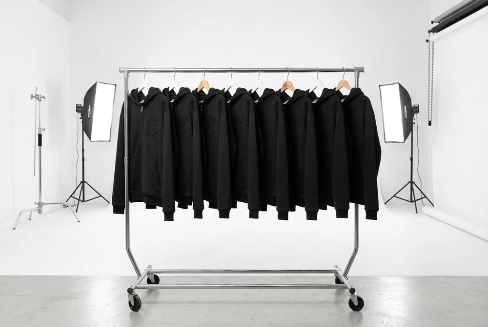 Rail of black ELEGANT hoodies hanging in a photo studio